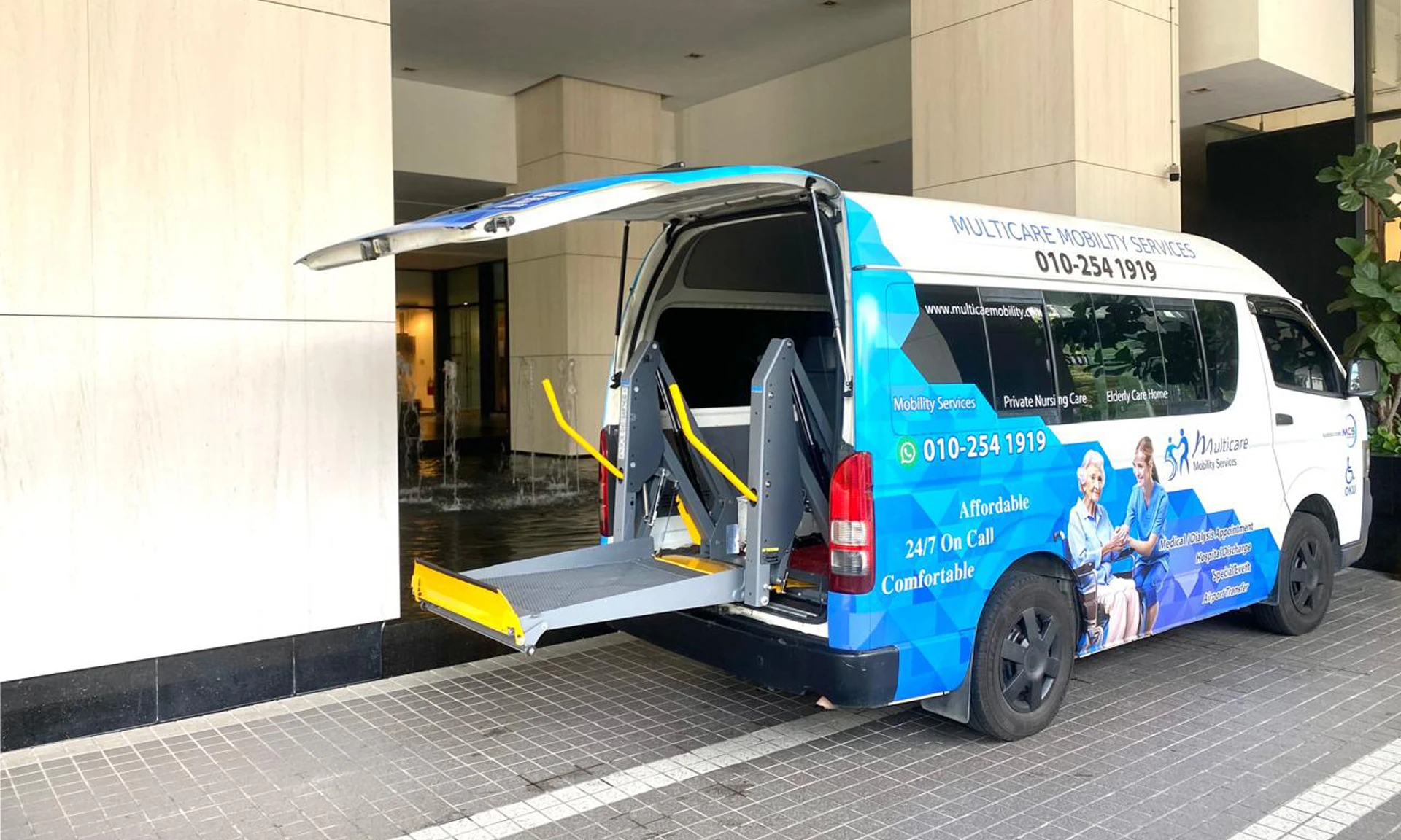 Multicare wheelchair van with hydraulic lift at a hospital entrance